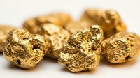 Golden metal nuggets with rough textured surface scattered on neutral background for investment and precious metals concepts.