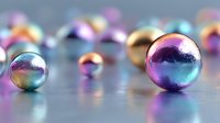 Colorful iridescent metallic spheres with rainbow reflections on smooth surface, creating dreamy bokeh effect for luxury product photography or abstract art background.