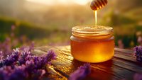 Golden honey dripping from wooden dipper into glass jar surrounded by purple lavender flowers in sunlit field. Perfect for food, wellness, and natural product marketing.