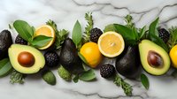 Fresh avocados, oranges, blackberries and green herbs arranged in row on white marble background, healthy organic food composition for cooking.