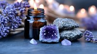 Amethyst crystal cluster with essential oil bottle, burning candle and lavender flowers on dark stone background creating peaceful spa atmosphere.