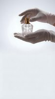 Hands gently protecting crystal perfume bottle with golden cap on white background for luxury fragrance and cosmetics advertising.