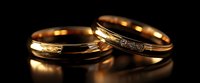 Elegant gold wedding rings with delicate diamond accents on dark background, romantic symbol of eternal love and marriage commitment.