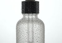 Glass dropper bottle with water condensation droplets on surface against white background, used for essential oils or cosmetic serums.