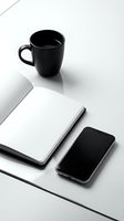 Minimalist black and white workspace with open notebook, smartphone with blank screen, and coffee mug on white desk surface.