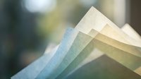 Colorful textured paper samples fanned out showing various pastel shades and textures for crafting, scrapbooking, and creative design projects.