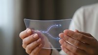 Hands holding transparent flexible glass display with glowing arrow icon, showcasing futuristic technology innovation and next-generation digital interface design.