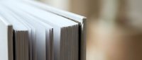 Close-up of open book pages with shallow depth of field showing paper texture and binding details for educational and literary content.