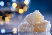Raw organic sugar cubes with crystalline texture against blurred bokeh lights background, creating magical winter atmosphere for food photography and design.