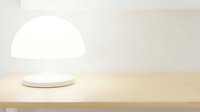 Glowing white dome lamp on wooden surface emits soft ambient light, suitable for interior design, home decor, and product photography applications.