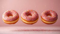 Pink glazed donuts with colorful sprinkles floating in row against pastel background, sweet dessert food photography with falling sugar decoration.