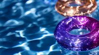 Vibrant purple swim ring floating on rippling blue pool water with sunlight reflections creating dynamic light patterns and summer atmosphere.