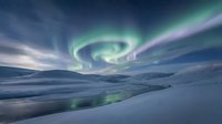 Spectacular aurora borealis swirling over snowy arctic landscape with frozen river reflecting green northern lights in twilight sky.