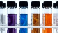 Laboratory test tubes with colorful chemical solutions in rack for scientific research and analysis experiments.