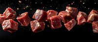 Raw beef chunks floating on black background with spices. Fresh cut meat cubes in motion with seasoning particles for restaurant menu or cooking concept.