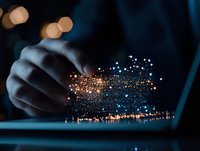 Magical glowing particles floating above laptop keyboard with hands typing in dark room, creating ethereal digital transformation atmosphere for technology concept.