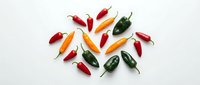 Colorful hot chili peppers arranged on white background. Fresh spicy vegetables including red, orange and green varieties for cooking and seasoning.