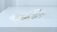 Medical protective equipment with disposable gloves and sanitizer bottle on clean white surface for healthcare safety and hygiene protocols.