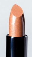 Peach shimmering lipstick bullet close-up on white background showcasing metallic nude color and glossy texture for beauty and cosmetic advertising.