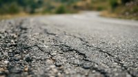 Close-up of asphalt road surface with textured pavement and blurred background, suitable for transportation, infrastructure, and construction design projects.