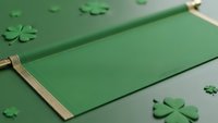 Green paper shamrocks scattered around blank card with golden ribbon for St. Patrick's Day greeting design and festive celebration crafts.