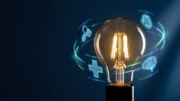 Vintage Edison bulb with glowing filament surrounded by floating medical icons including cross, brain, heart on dark blue background for healthcare innovation.