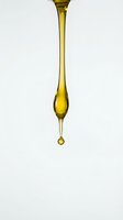 Golden oil drop falling from spoon on white background isolated for cooking and culinary design projects.