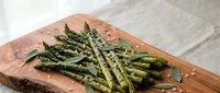 Grilled asparagus spears with herbs and seasoning on rustic wooden cutting board, healthy vegetable side dish for cooking and culinary presentations.