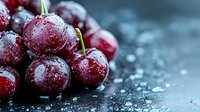 Fresh ripe red cherries with water drops and frost crystals on dark background, macro shot showing juicy texture and natural freshness of seasonal fruit.
