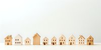 Wooden miniature houses arranged in row on white background for real estate and property development concepts.