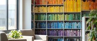 Modern home library with rainbow color-coded bookshelf organization system creating vibrant gradient display in contemporary living room interior.