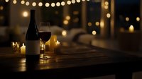 Red wine glass and bottle on wooden table with romantic candlelight and string lights creating cozy evening atmosphere. Festive dining setup for special occasion.