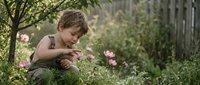 Young boy exploring nature in garden, discovering flowers and plants outdoors. Child development, curiosity, environmental education, outdoor play concept.