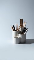 Modern white ceramic desk organizer with pencils pens and art supplies on clean minimalist background for office workspace and creative studio organization.