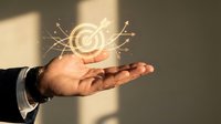 Businessman hand presenting glowing target with arrows concept for goal achievement and business success strategy planning.
