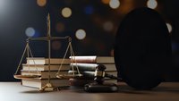Golden scales of justice with gavel and law books on wooden desk against bokeh background for legal services and courtroom concepts.