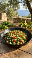 Mediterranean tabbouleh salad with fresh parsley, tomatoes, and cucumbers served in black bowl on wooden table outdoors.
