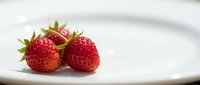 Fresh ripe strawberries on white plate for healthy eating, cooking recipes, desserts and organic fruit concepts in kitchen setting.