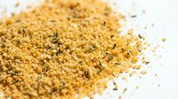 Pile of golden granulated sugar crystals scattered on white surface, suitable for food photography, baking, and culinary design projects.