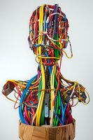 Artistic sculpture of human bust made from colorful electrical wires and cables, symbolizing technology and connectivity in modern digital age against white background.