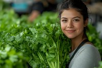 Young woman with dark hair and olive complexion holding fresh green leafy vegetables in an outdoor garden setting, promoting healthy eating and organic farming.