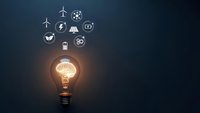 Glowing light bulb with travel and transportation icons floating above on dark blue background representing innovation and journey planning concepts.