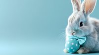 Adorable white bunny wearing turquoise polka dot bow tie next to matching Easter egg against blue background, festive spring holiday composition.