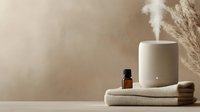 Modern minimalist essential oil diffuser with steam on neutral beige background, spa wellness aromatherapy setup with towels and amber bottle for relaxation.