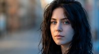 Young brunette woman with tousled hair and intense gaze in soft natural lighting. Professional headshot portrait for lifestyle and beauty concepts.