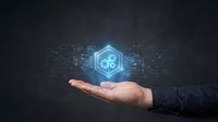Male hand holding a glowing hexagon with gears and circuit board elements on dark background, symbolizing technology and innovation.