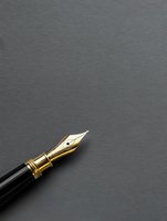 Golden fountain pen nib on dark gray background with copy space, elegant writing instrument for professional correspondence and calligraphy.