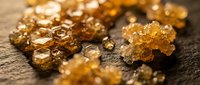 Raw gold nuggets and flakes scattered on dark textured surface showcasing natural precious metal mining discovery and wealth investment opportunities.
