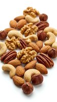 Mixed nuts collection with almonds, walnuts, cashews, pecans and hazelnuts scattered on white background for healthy snacking and cooking recipes.