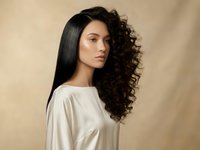Young mixed-race woman with contrasting straight and curly hair textures showcasing dual hair styling concept for beauty salon and hair care treatments.